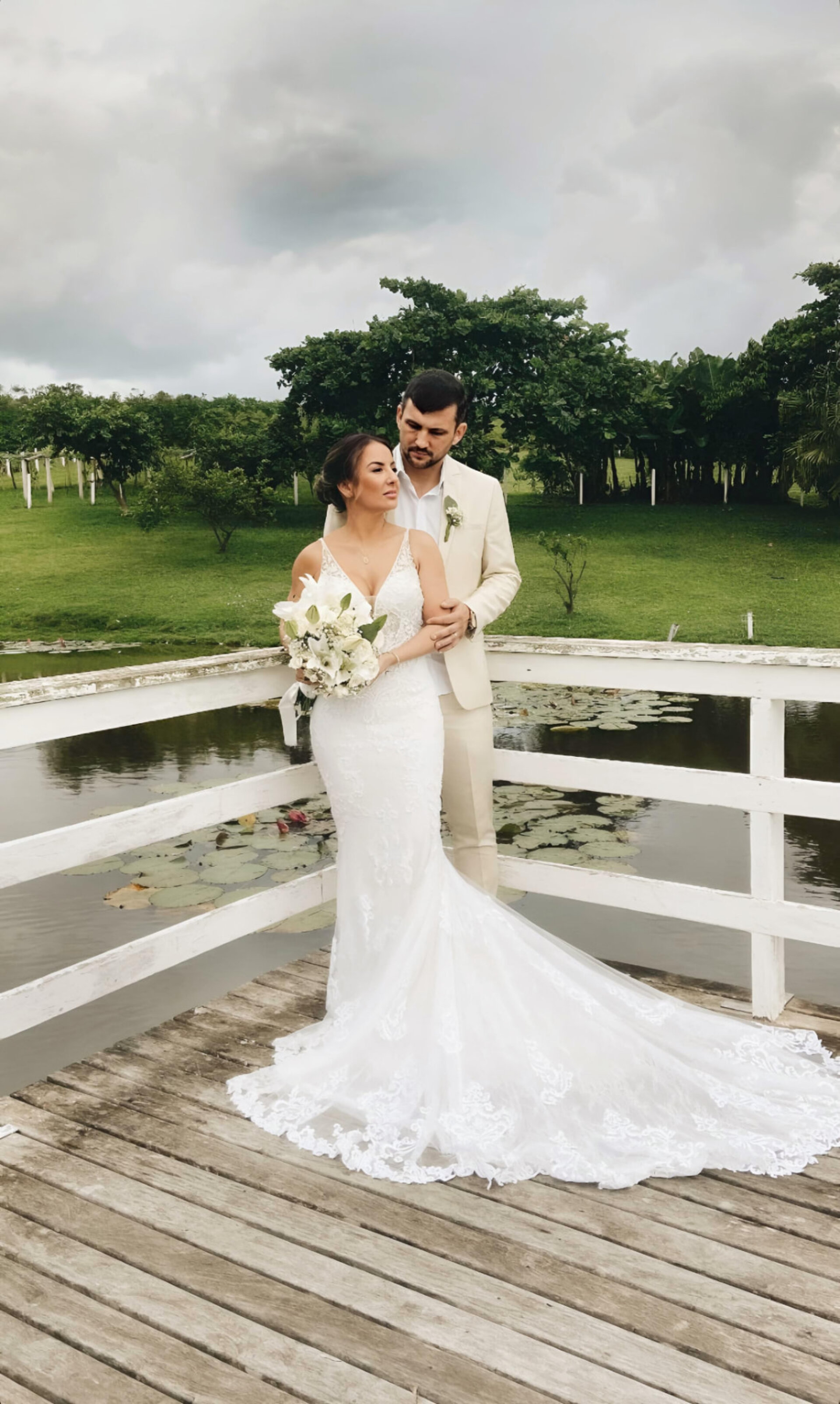 Casal de noivos abraçado sobre a ponte branca do lago no Medeiros Garden